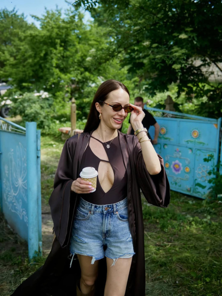 Горняк у шортах і чоботах в стилі бохо посвітила ніжками на тлі розписаних хатин в Мальованому селі. Фото