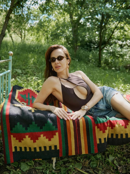 Горняк у шортах і чоботах в стилі бохо посвітила ніжками на тлі розписаних хатин в Мальованому селі. Фото