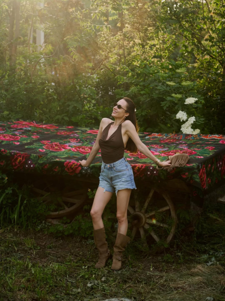 Горняк у шортах і чоботах в стилі бохо посвітила ніжками на тлі розписаних хатин в Мальованому селі. Фото